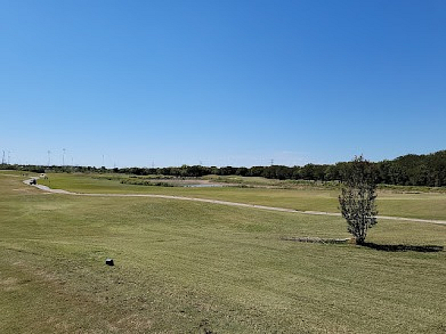 Expansive golf course view under a clear blue sky, perfect for outdoor enthusiasts seeking tranquility and leisure.