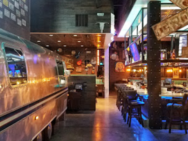 Trendy urban dining space featuring a vintage trailer decor, chic bar, and ambient lighting for a unique restaurant experience.