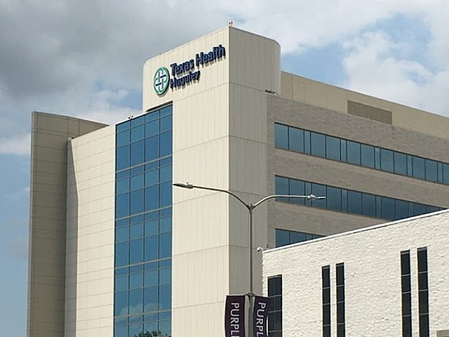 Modern healthcare facility with a sleek glass facade and ample parking.