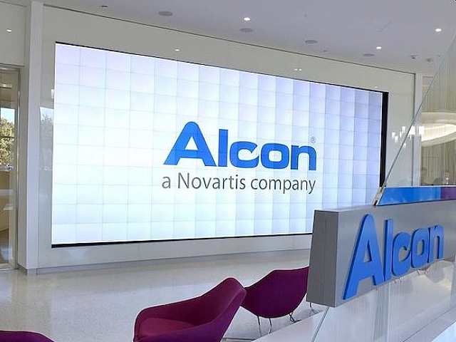 Modern lobby with sleek design and vibrant seating area, featuring a prominent display of the Alcon company logo.