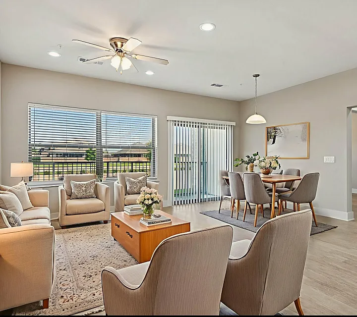 Modern open-concept living and dining area with stylish beige seating, elegant decor, and abundant natural light from large windows.