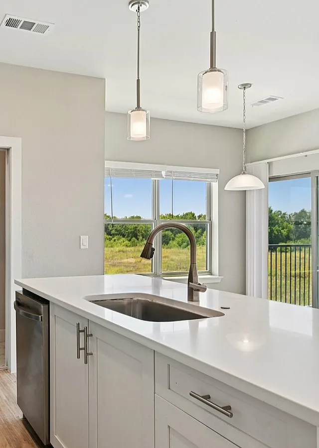 Bright, modern kitchen with sleek white cabinets, a large island, and stainless steel appliances, overlooking a scenic outdoor view.