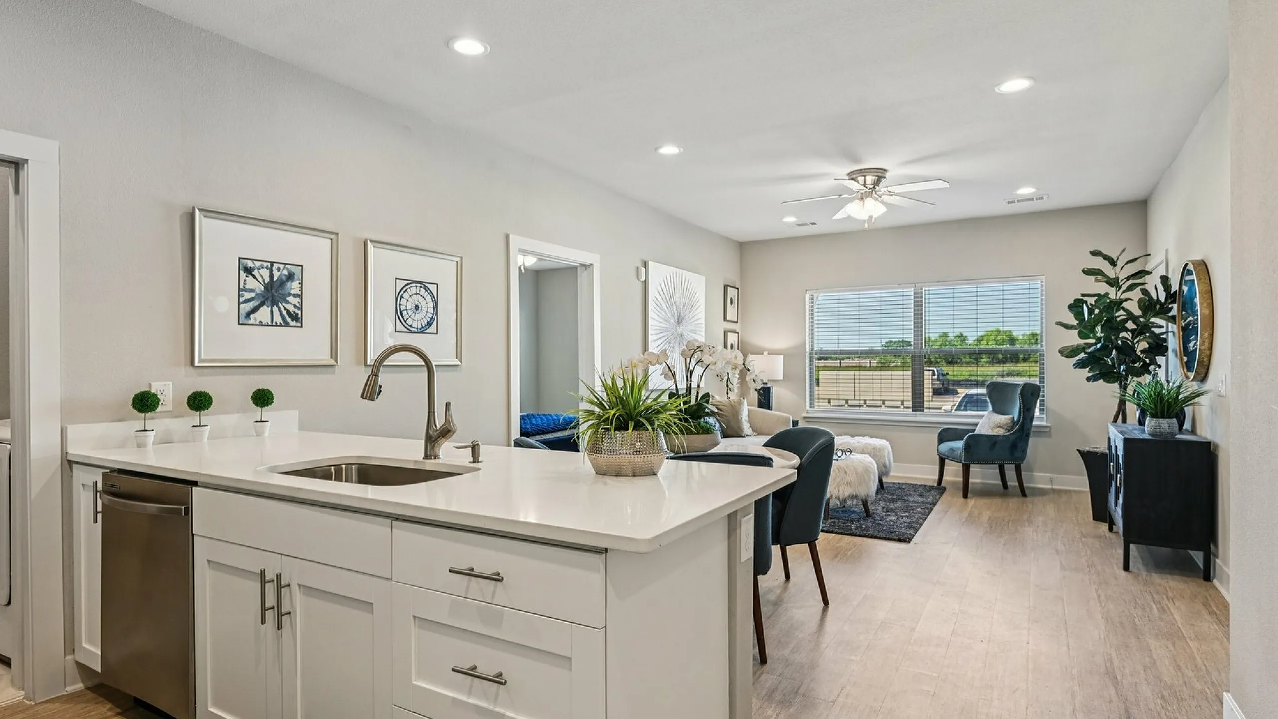 Bright and modern open-plan living area featuring a sleek kitchen with stainless steel appliances, comfortable lounge with cozy furnishings, and large window offering natural light.