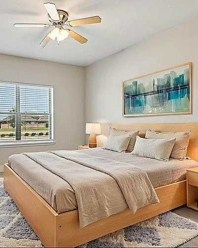 Inviting bedroom with modern decor, featuring a cozy bed, elegant wooden furniture, and a serene view through a large window.
