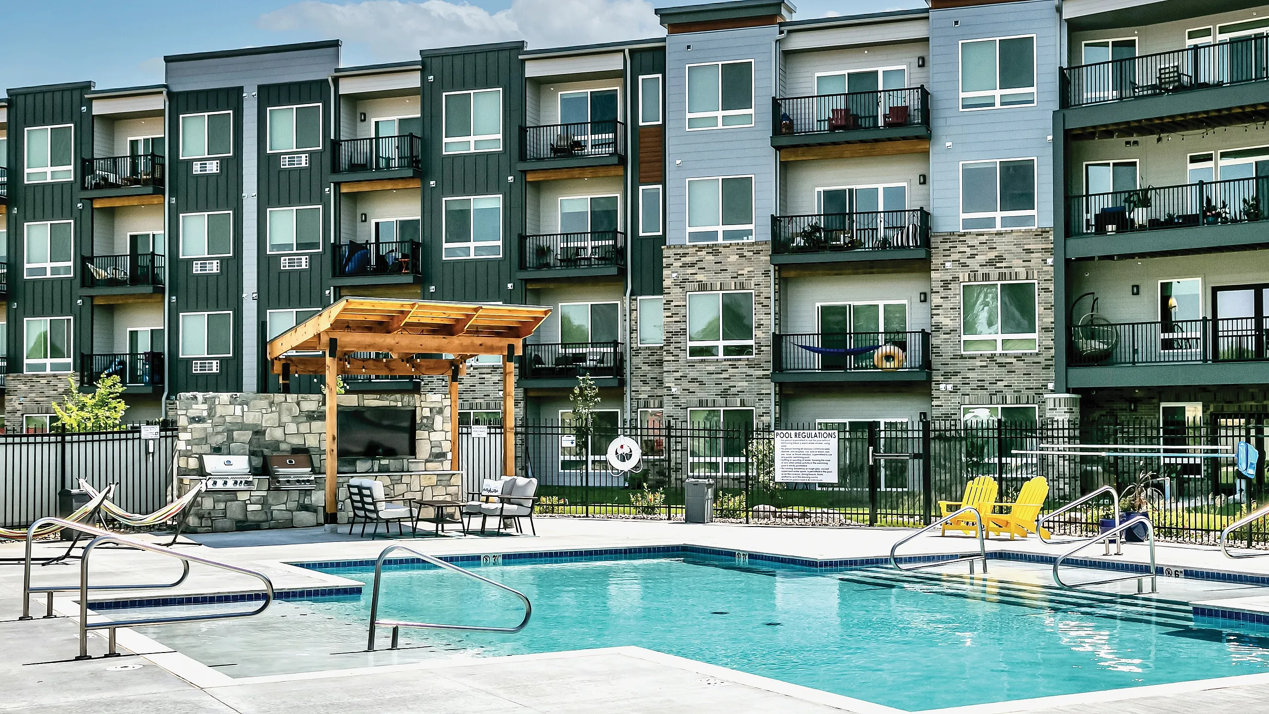 Modern apartment complex featuring a luxurious outdoor pool area, stylish facade, and private balconies.
