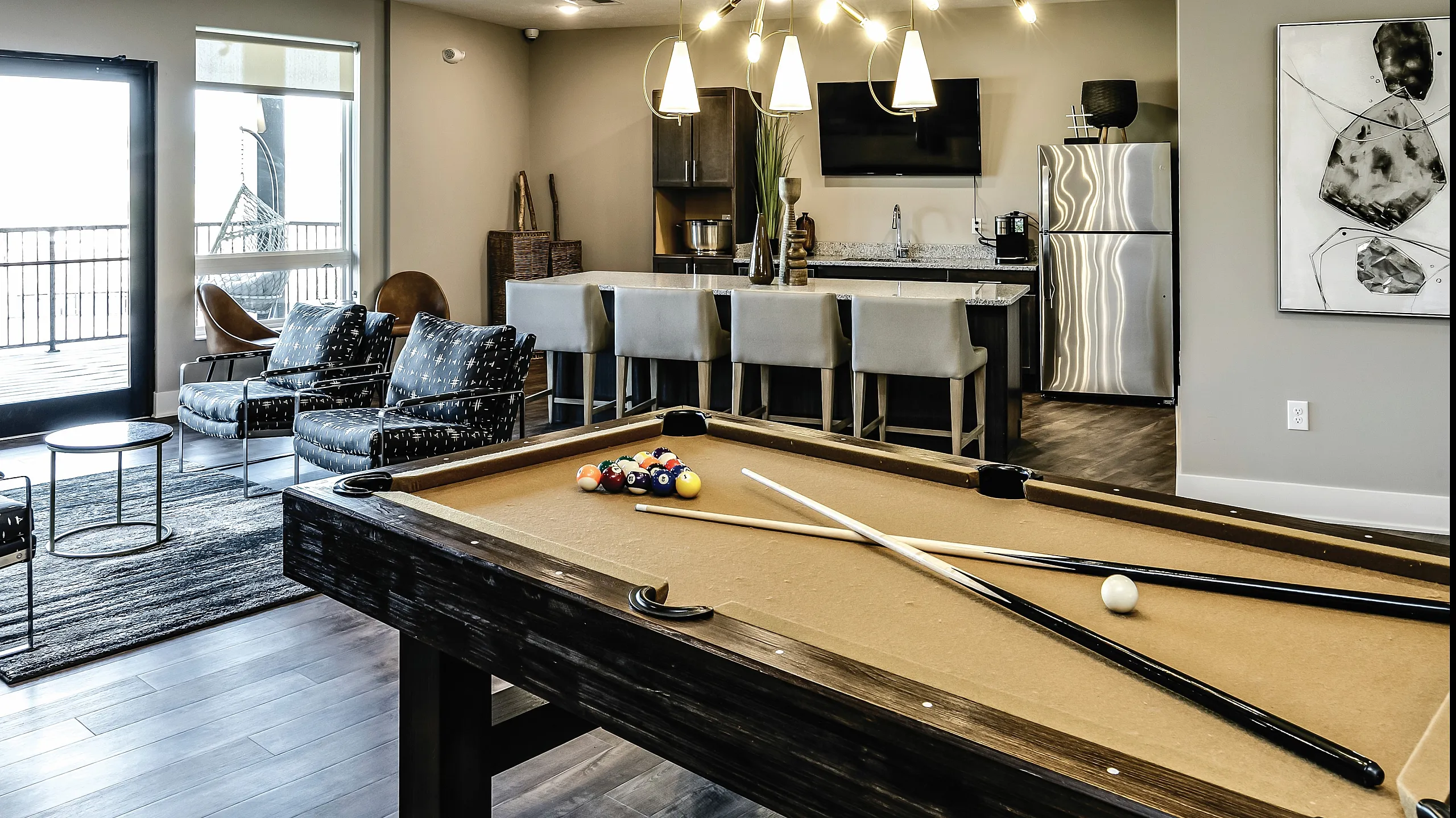 Chic apartment lounge featuring a modern billiards table, stylish seating area, and an elegant open kitchen with contemporary lighting.