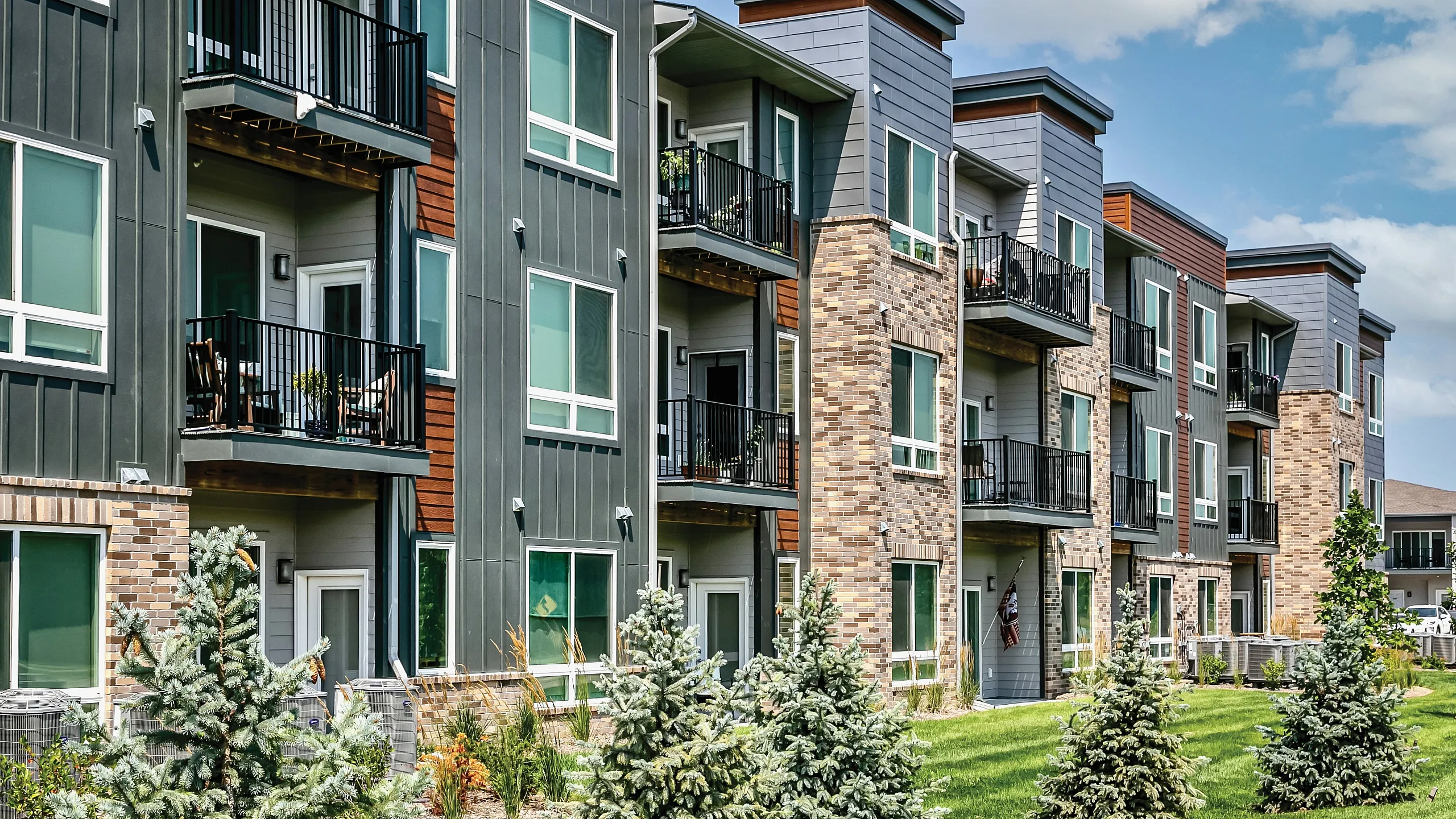Modern apartment complex with sleek balconies and lush greenery, offering stylish living spaces and vibrant community life.