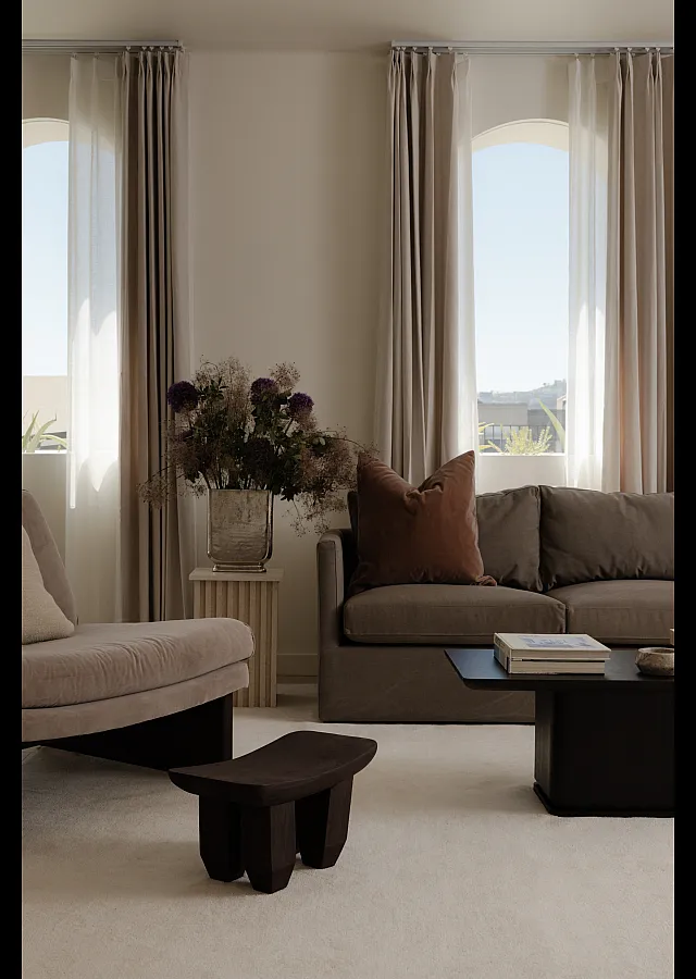 Elegant living room with plush brown sofa, chic coffee table, and decorative floral arrangement under soft natural light.