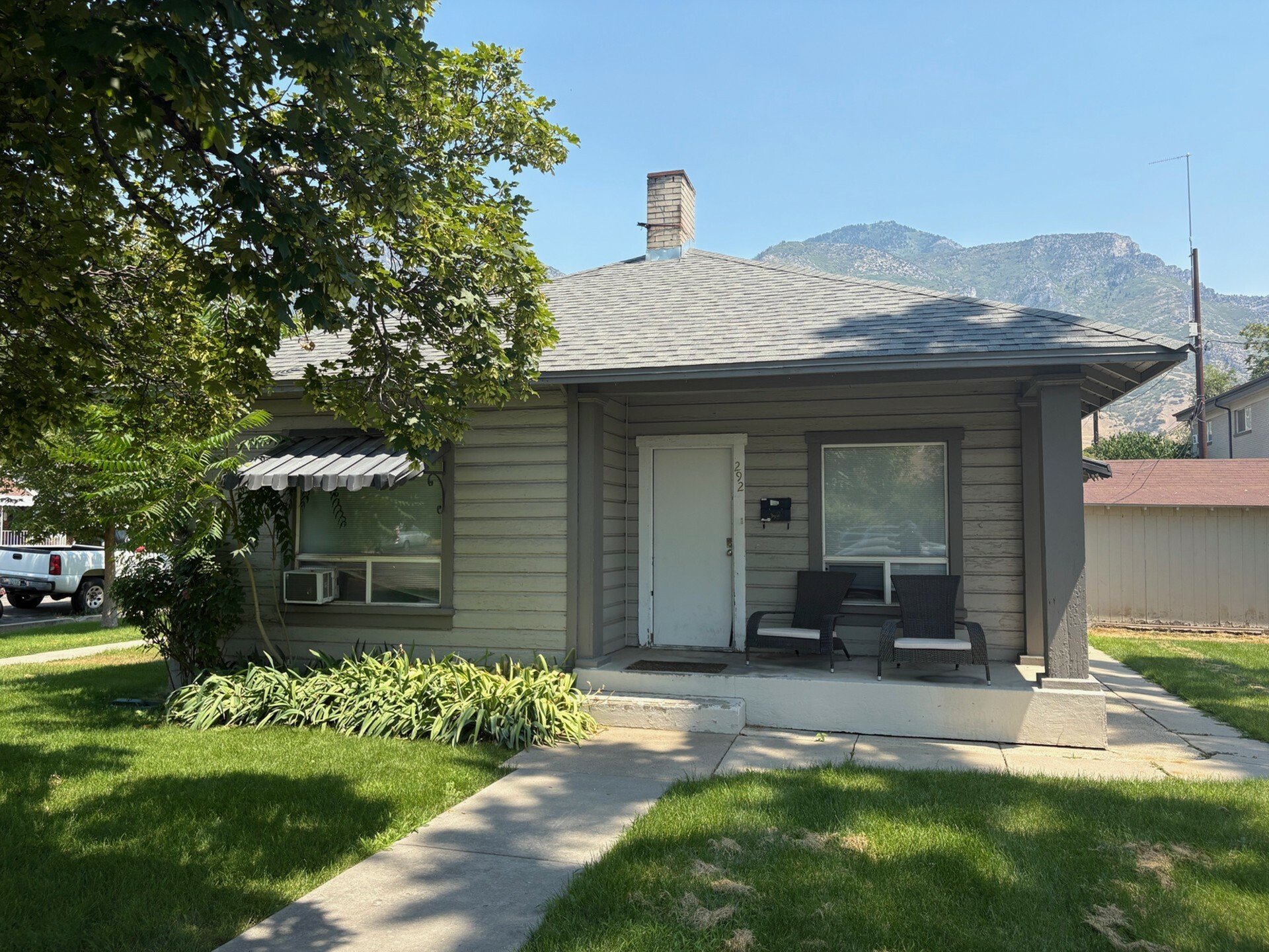 Charming single-story home with cozy front porch, surrounded by lush greenery and stunning mountain views.