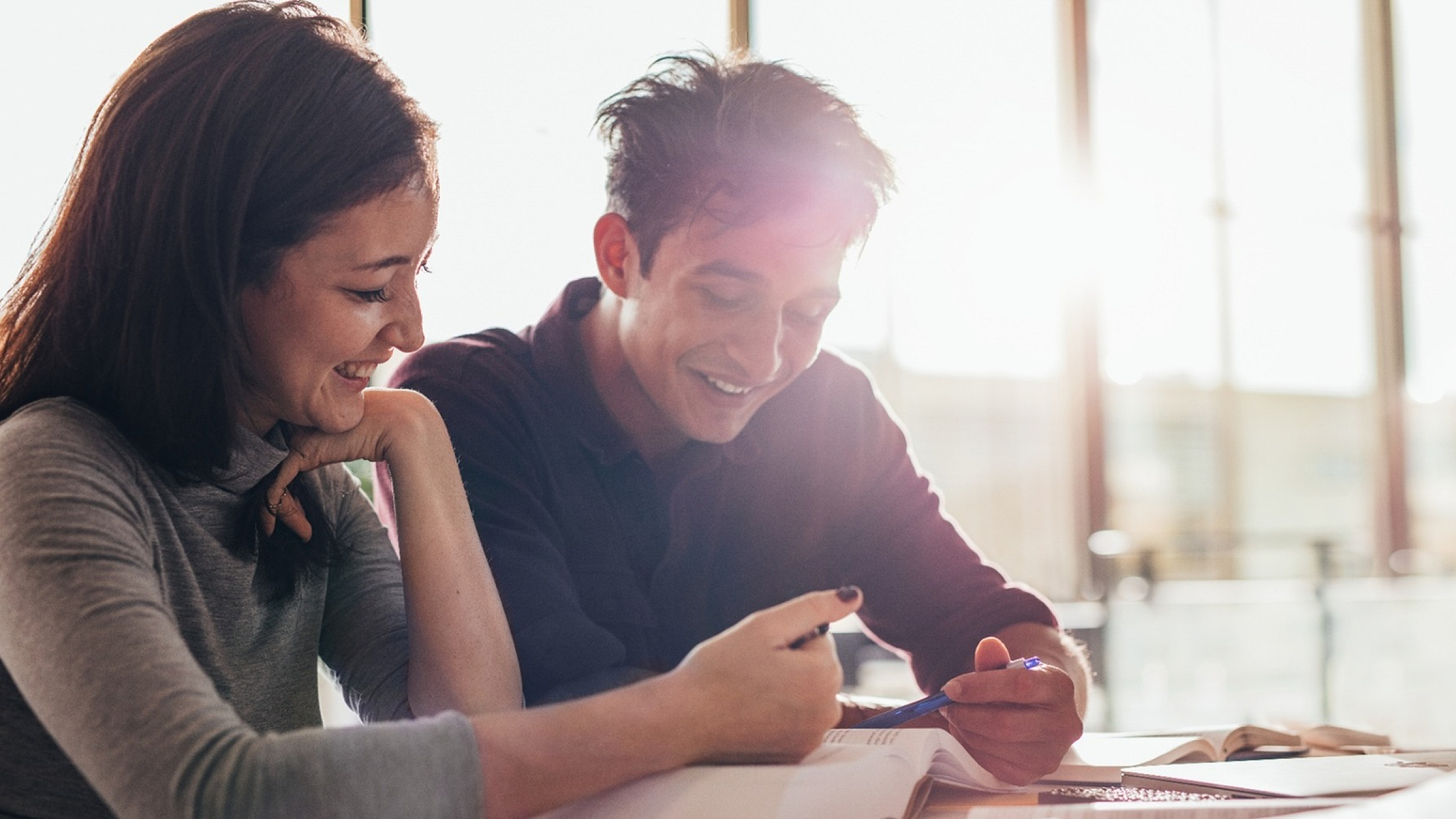 Two people enjoying a lively study session in a sunlit room.