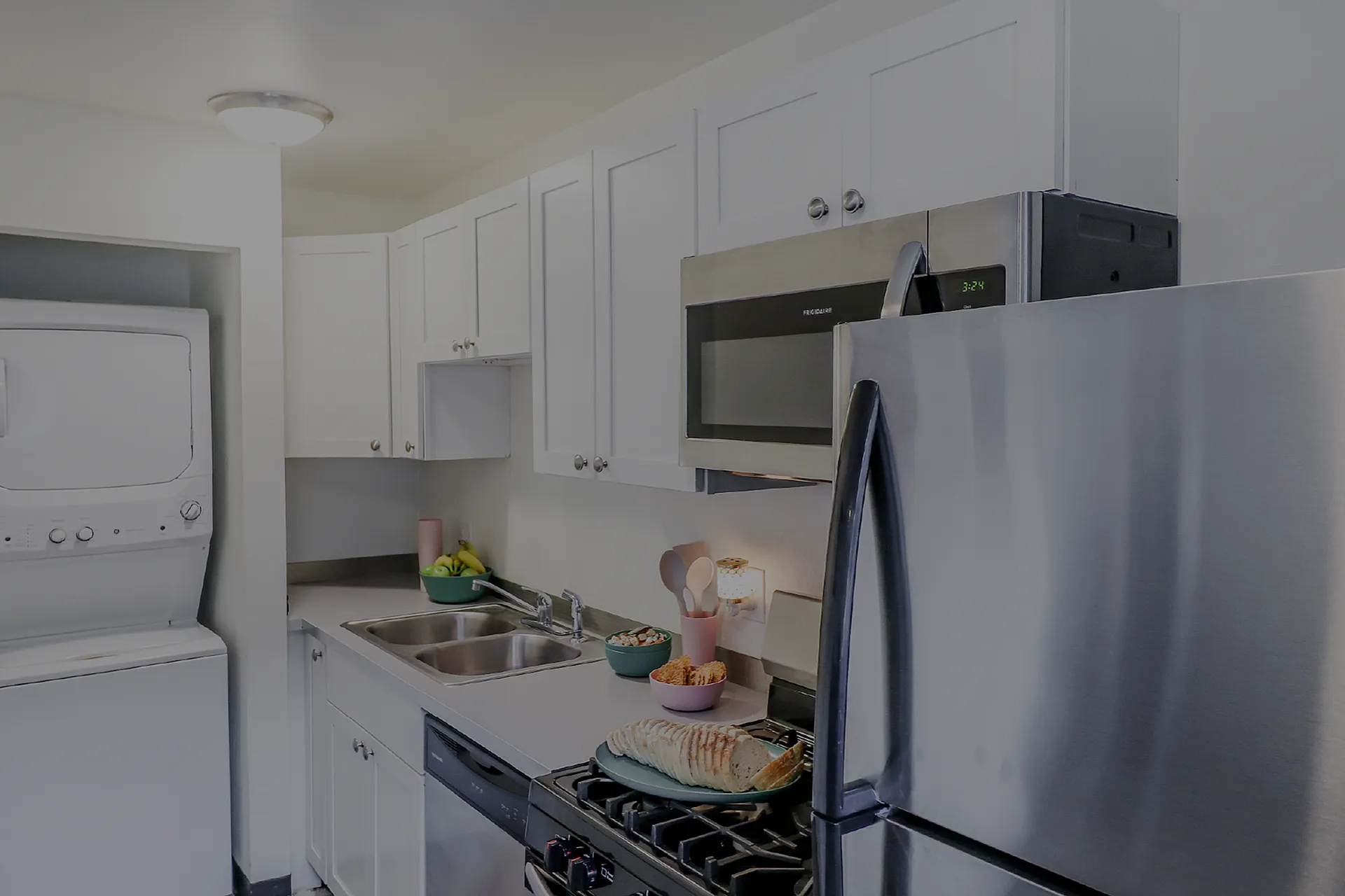 Modern kitchen with stainless steel appliances, sleek white cabinets, and in-unit washer and dryer for ultimate convenience.