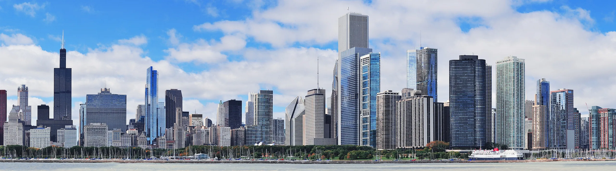 Stunning panoramic view of a vibrant city skyline with modern skyscrapers and a waterfront, under a bright blue sky.