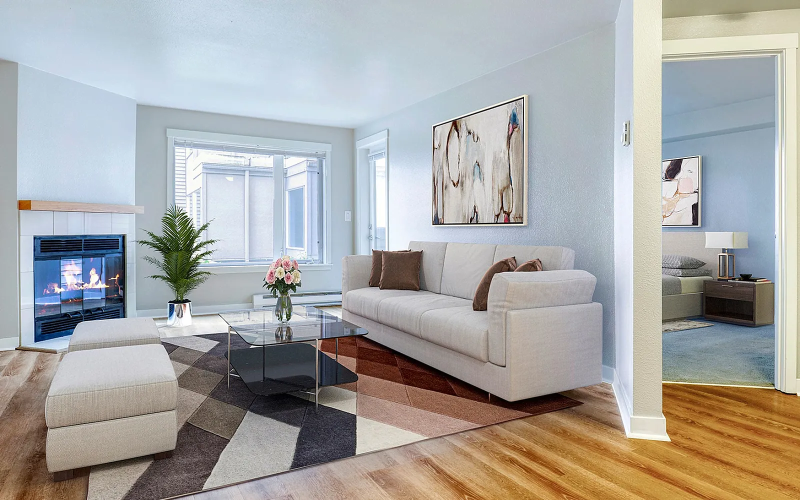 Bright and inviting living room with modern decor, featuring a cozy fireplace, plush sofa, and elegant artwork, complemented by warm wooden flooring.
