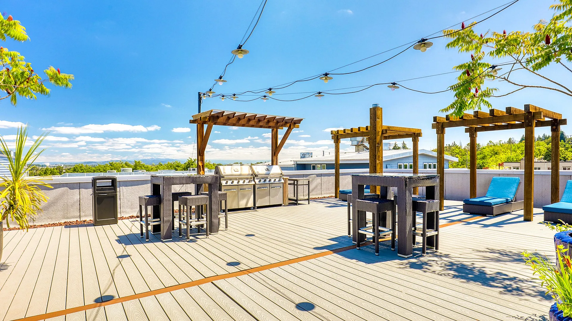 Chic rooftop terrace with modern lounge chairs, stylish pergolas, and a well-equipped grilling area offering scenic views.