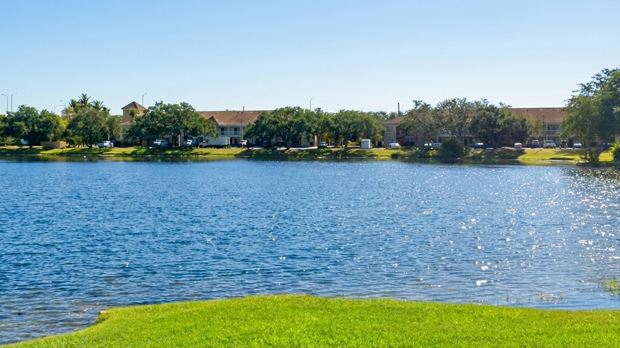 Charming lakeside apartment community nestled among lush greenery and sparkling blue waters, offering a serene and picturesque living environment.