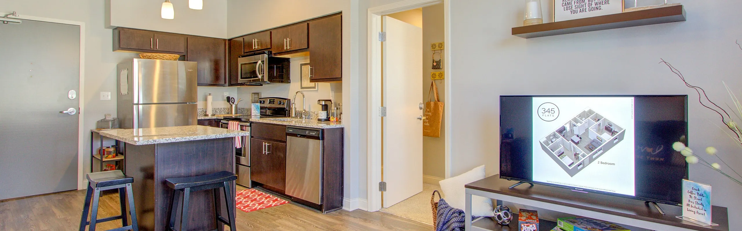 Contemporary open-plan living room and kitchen with sleek stainless steel appliances and stylish seating, perfect for modern living.