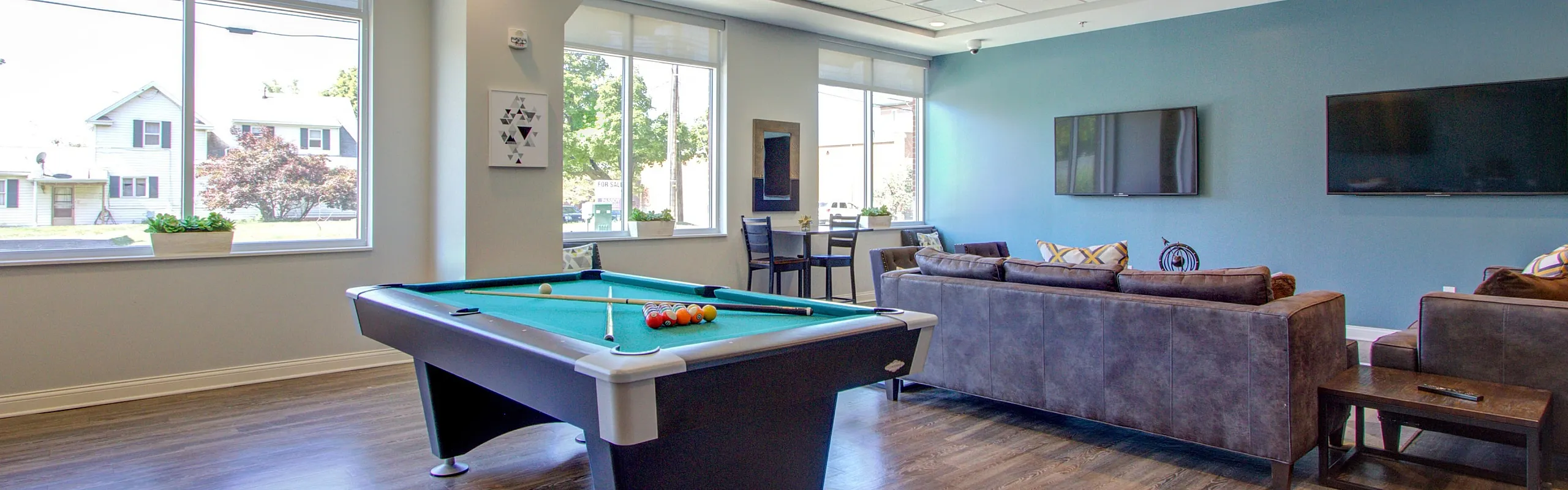 Stylish residential lounge with a modern pool table, plush seating, and large flat-screen TVs, perfect for entertainment and relaxation.