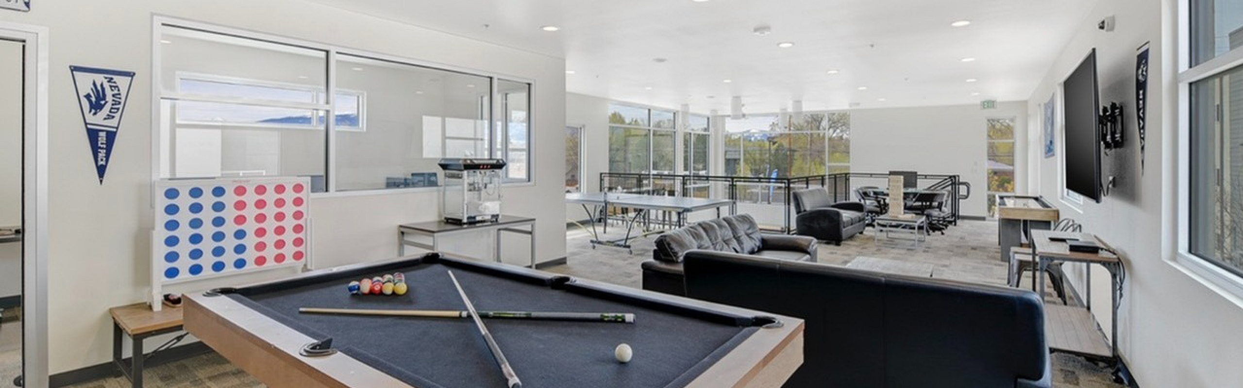 Bright and spacious game room featuring a pool table, Connect Four, modern furniture, and large windows offering scenic views.