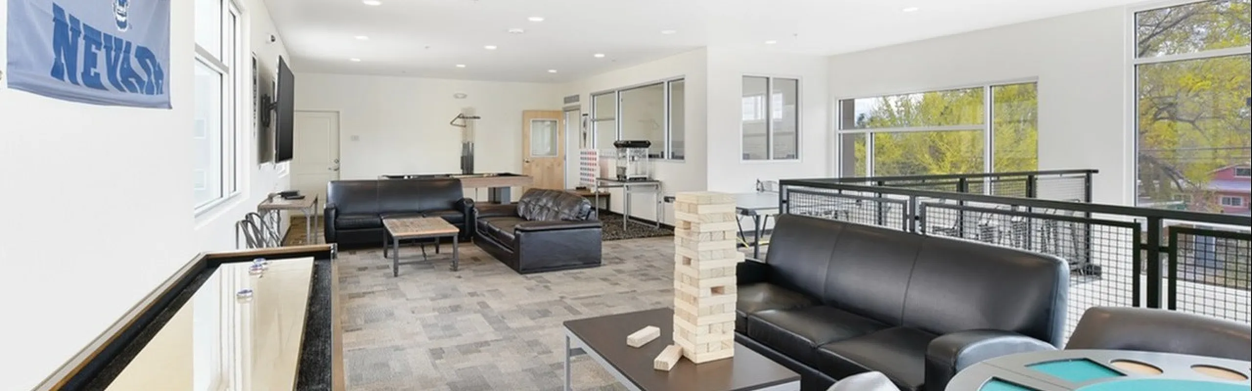 Stylish community lounge with modern leather seating, gaming tables, and a bright atmosphere perfect for relaxation or social gatherings.