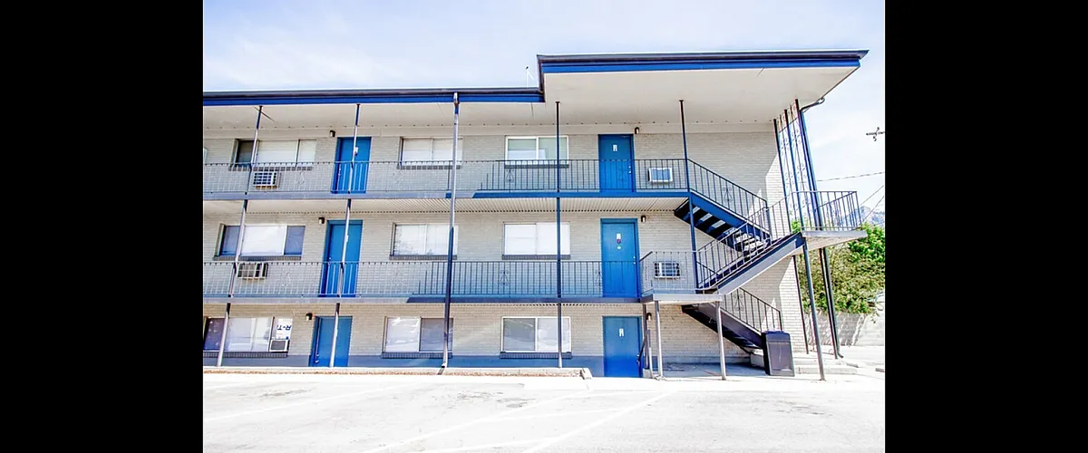 Modern three-story apartment building with vibrant blue accents and spacious balconies, offering a welcoming and convenient living space.