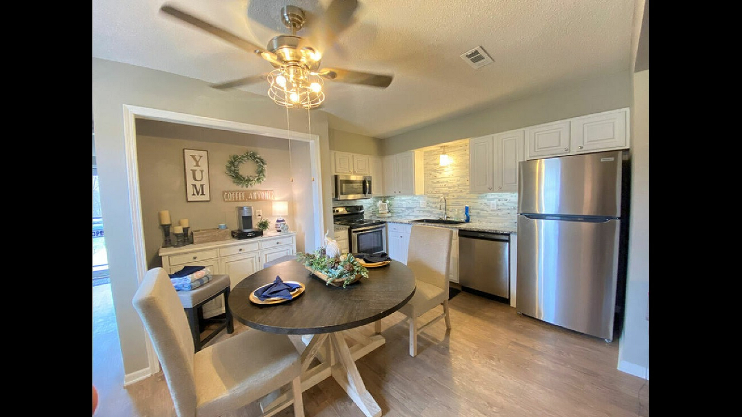 Well-designed kitchen with white cabinets, stainless steel appliances, and a dining area featuring a stylish wooden table.