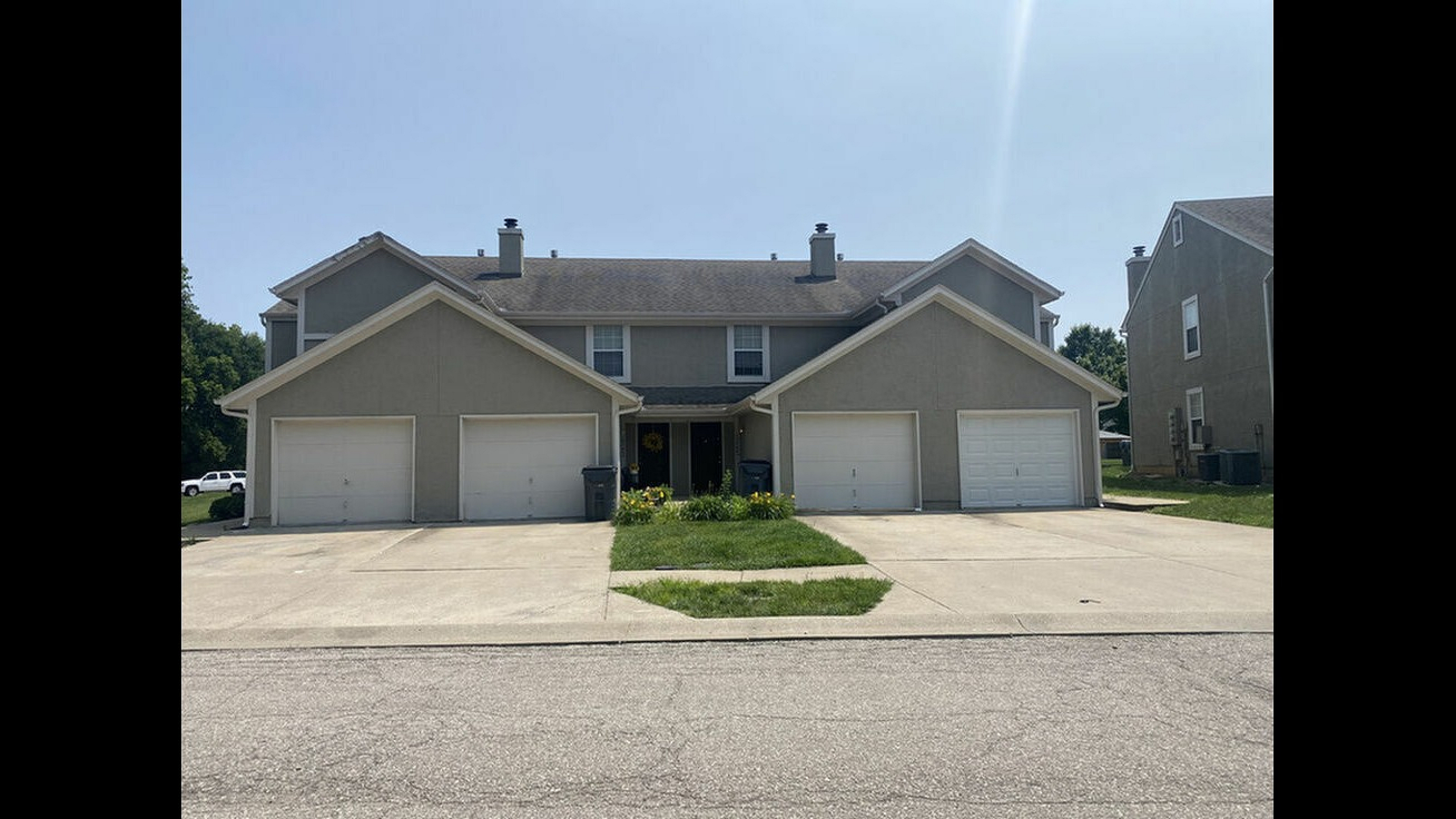 Charming suburban duplex with manicured lawn and spacious driveways, featuring a cozy and welcoming entrance.