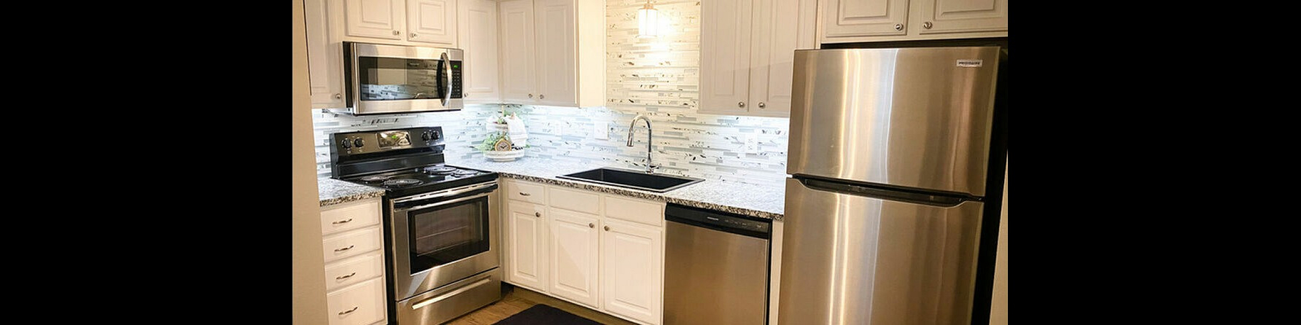 Contemporary kitchen with stainless steel appliances, white cabinetry, and elegant tiled backsplash.