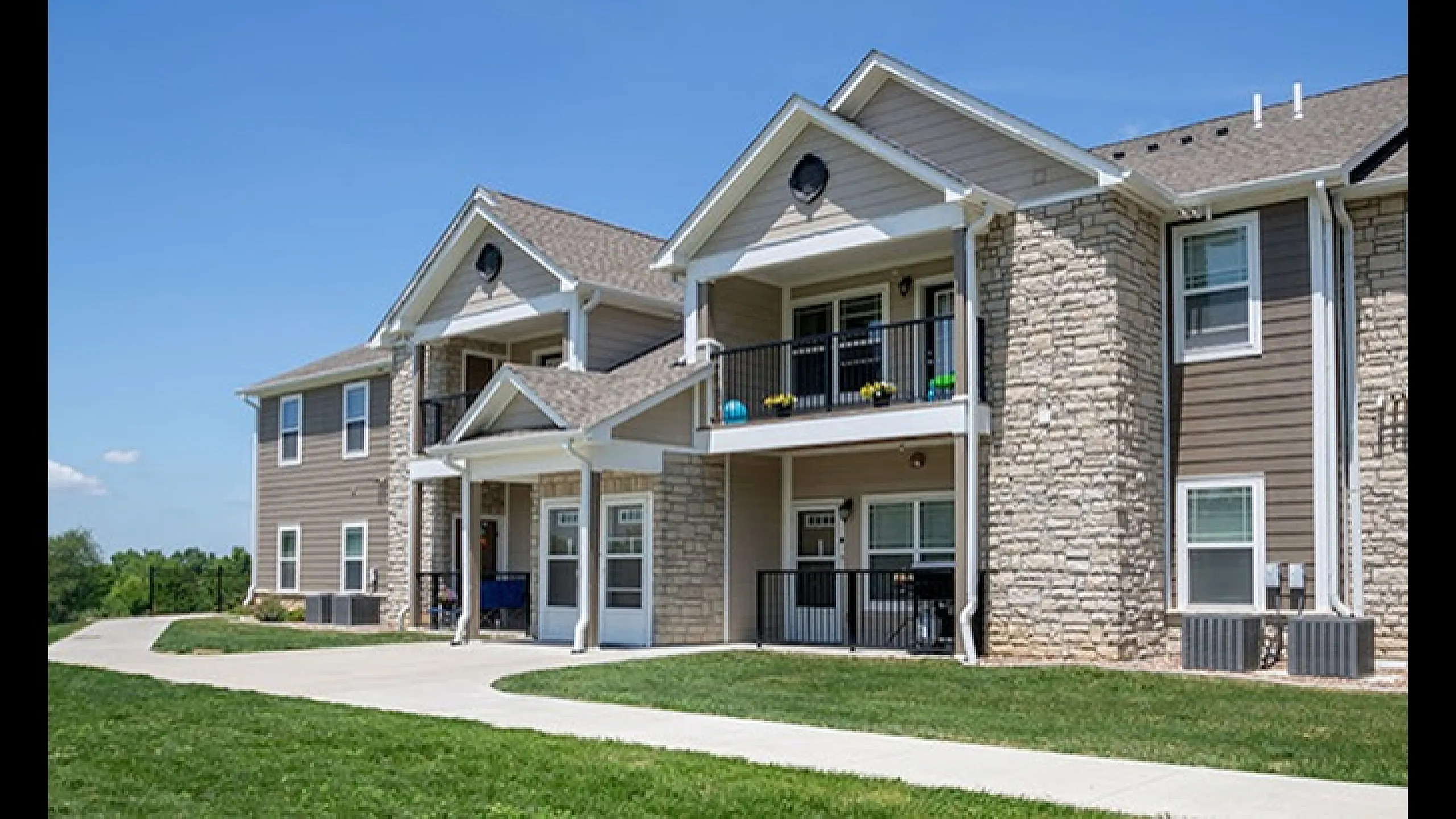 Beautiful apartment building with stone accents and balconies set against a scenic backdrop.