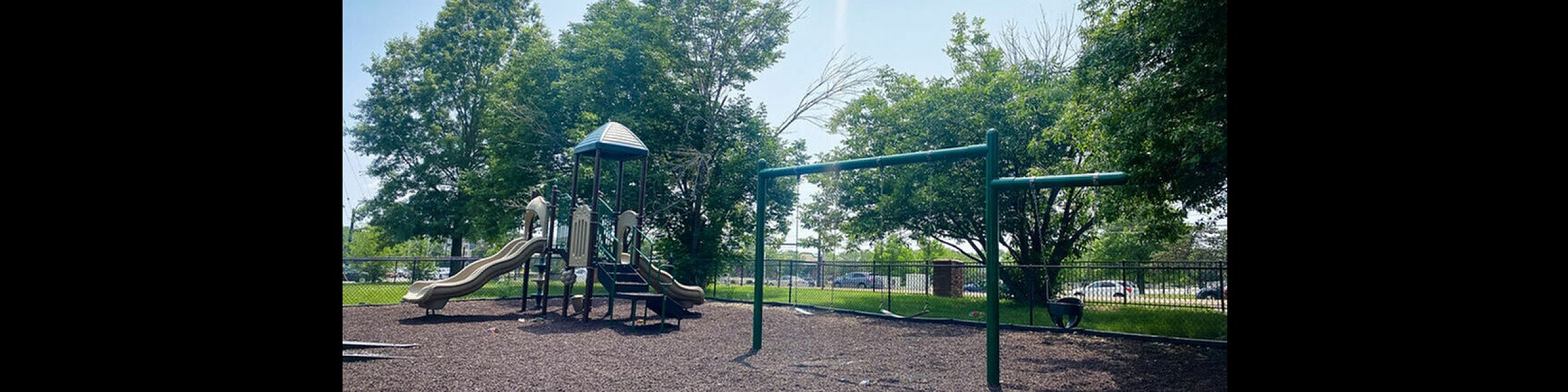Inviting playground with slides and swings surrounded by lush green trees, ideal for family fun.