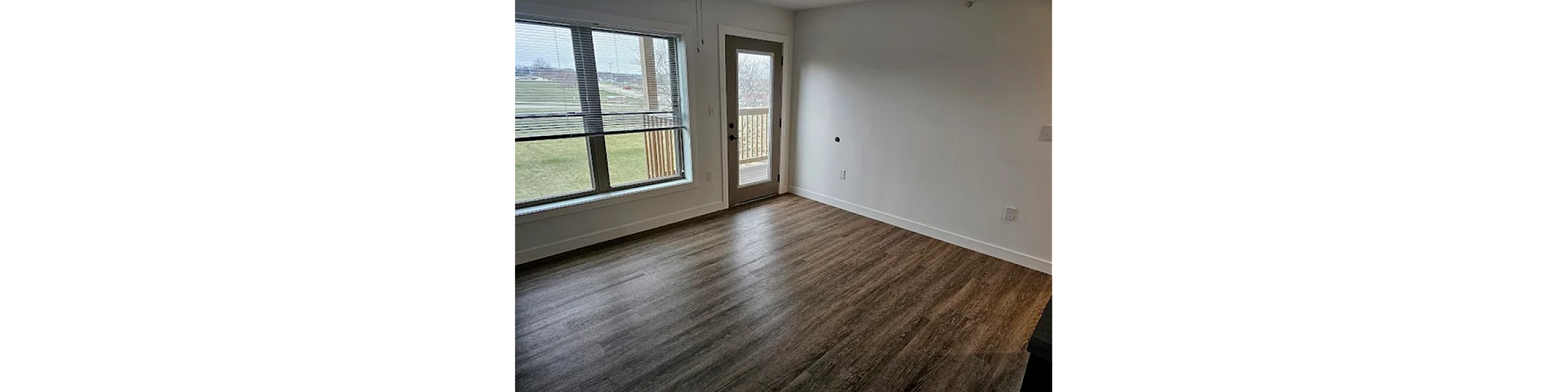 Bright and inviting living area with modern wood flooring, large window, and access to a private balcony with scenic views.