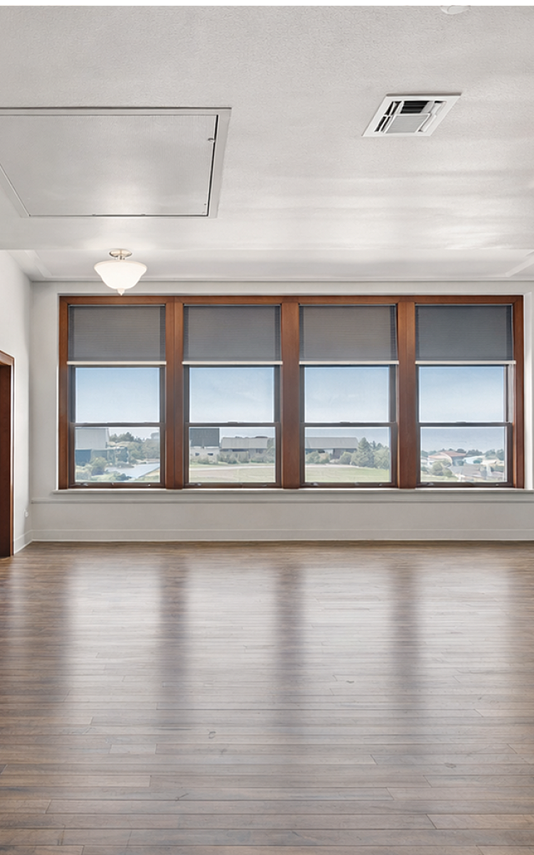 Bright open-plan living space with elegant wood flooring, large windows offering stunning views, and a modern kitchen with sleek cabinetry.