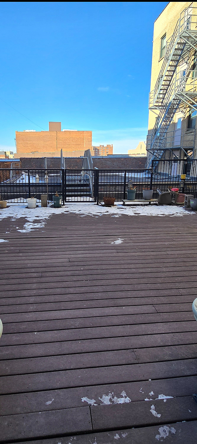 Spacious urban rooftop deck with stylish fencing, perfect for outdoor dining and entertainment, offering stunning city views.