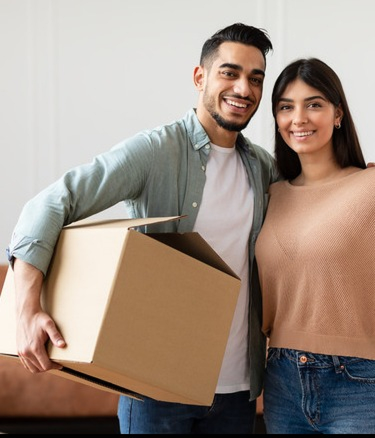 Happy couple holding keys and moving boxes in a beautifully decorated living room, celebrating their new home.