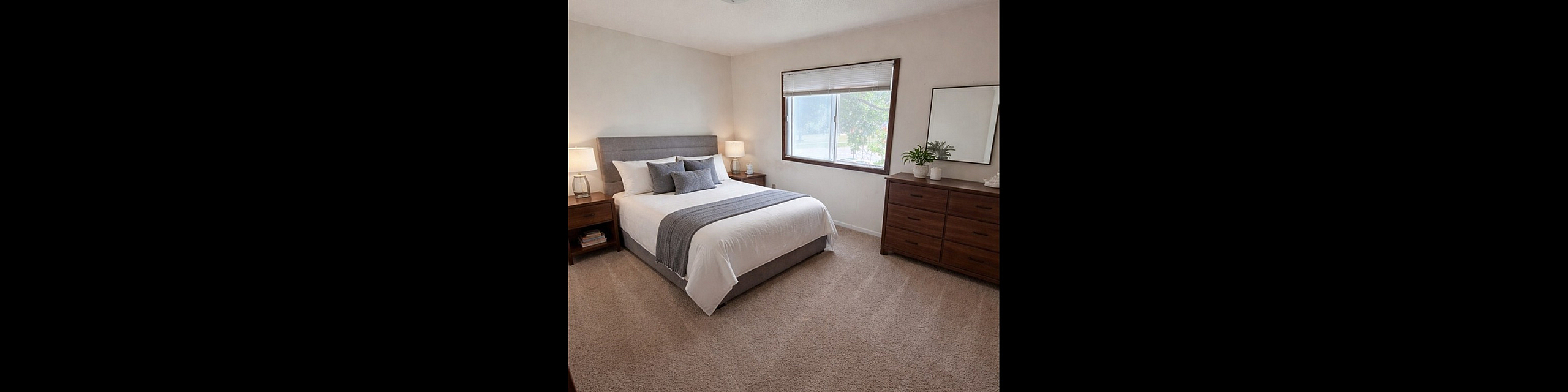 Inviting bedroom with cozy carpet, elegant decor, and abundant natural light from a large window.