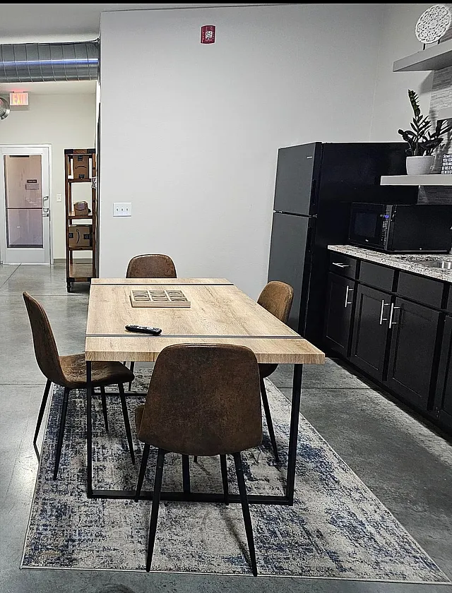 Modern industrial-style apartment featuring a cozy leather sofa, spacious dining area, and sleek kitchen setup with stainless steel appliances.