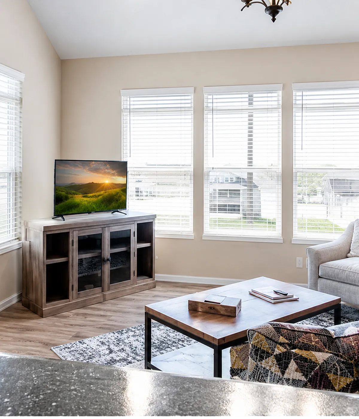 Bright and inviting living room with modern decor, large windows offering ample natural light, and a cozy seating area featuring a stylish coffee table and entertainment setup.