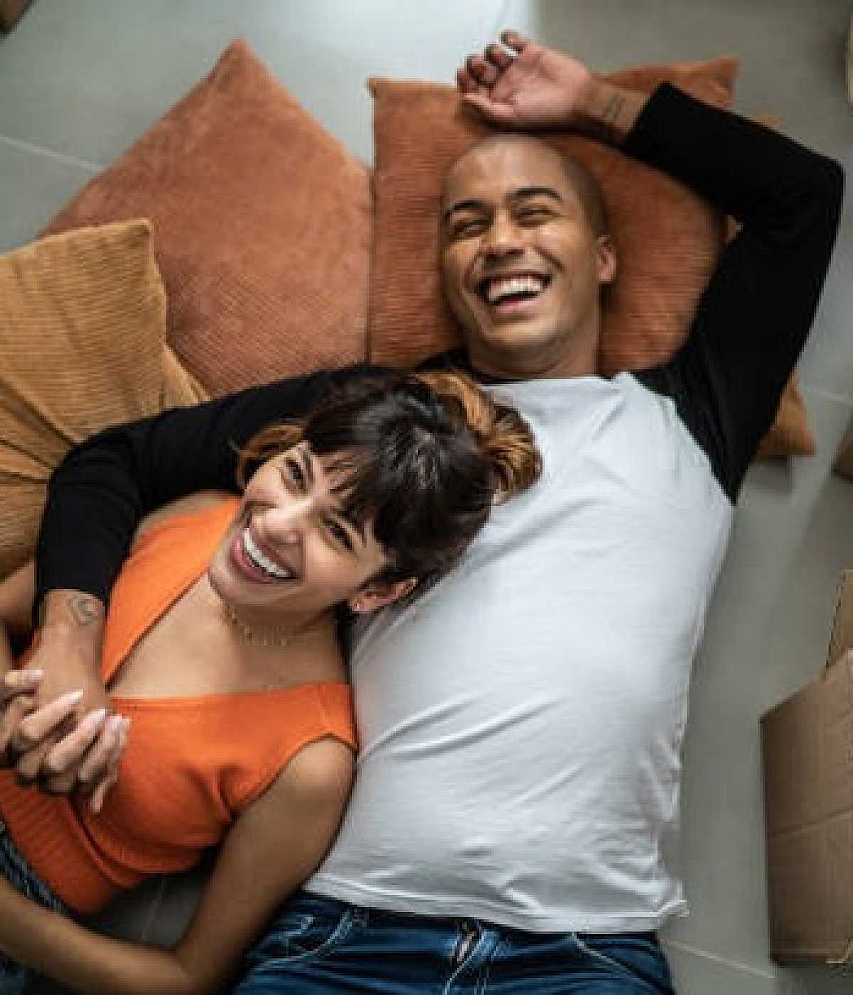Happy couple relaxing on a cozy floor surrounded by moving boxes, embracing the excitement of a new home.