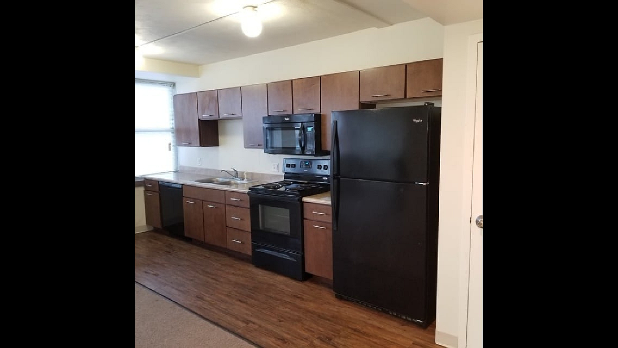 Modern kitchen with sleek dark appliances, ample wooden cabinetry, and stylish countertops offering a warm, inviting atmosphere.