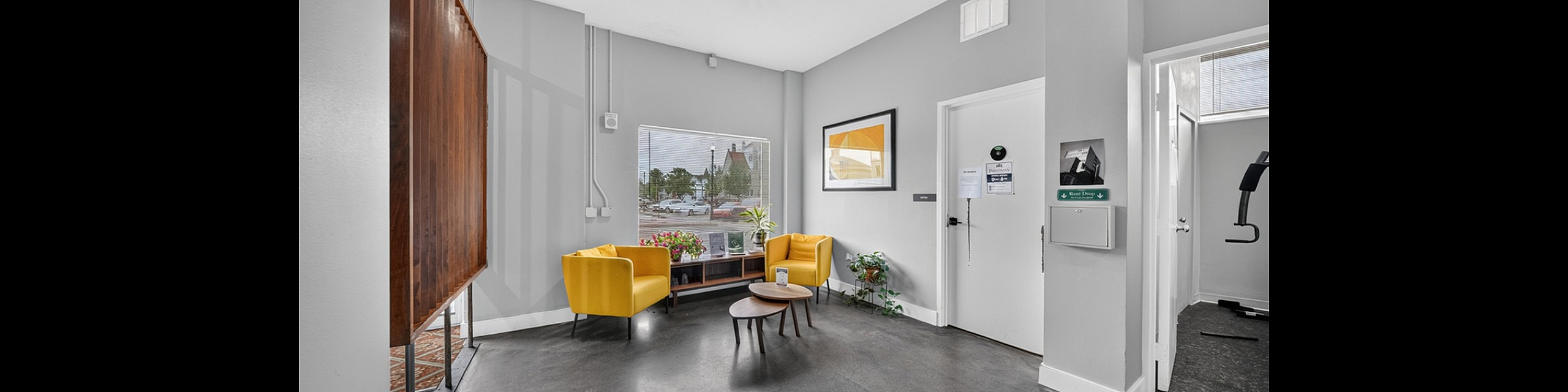 Inviting apartment lobby featuring vibrant yellow chairs, modern decor, and natural light streaming in for a warm and welcoming atmosphere.