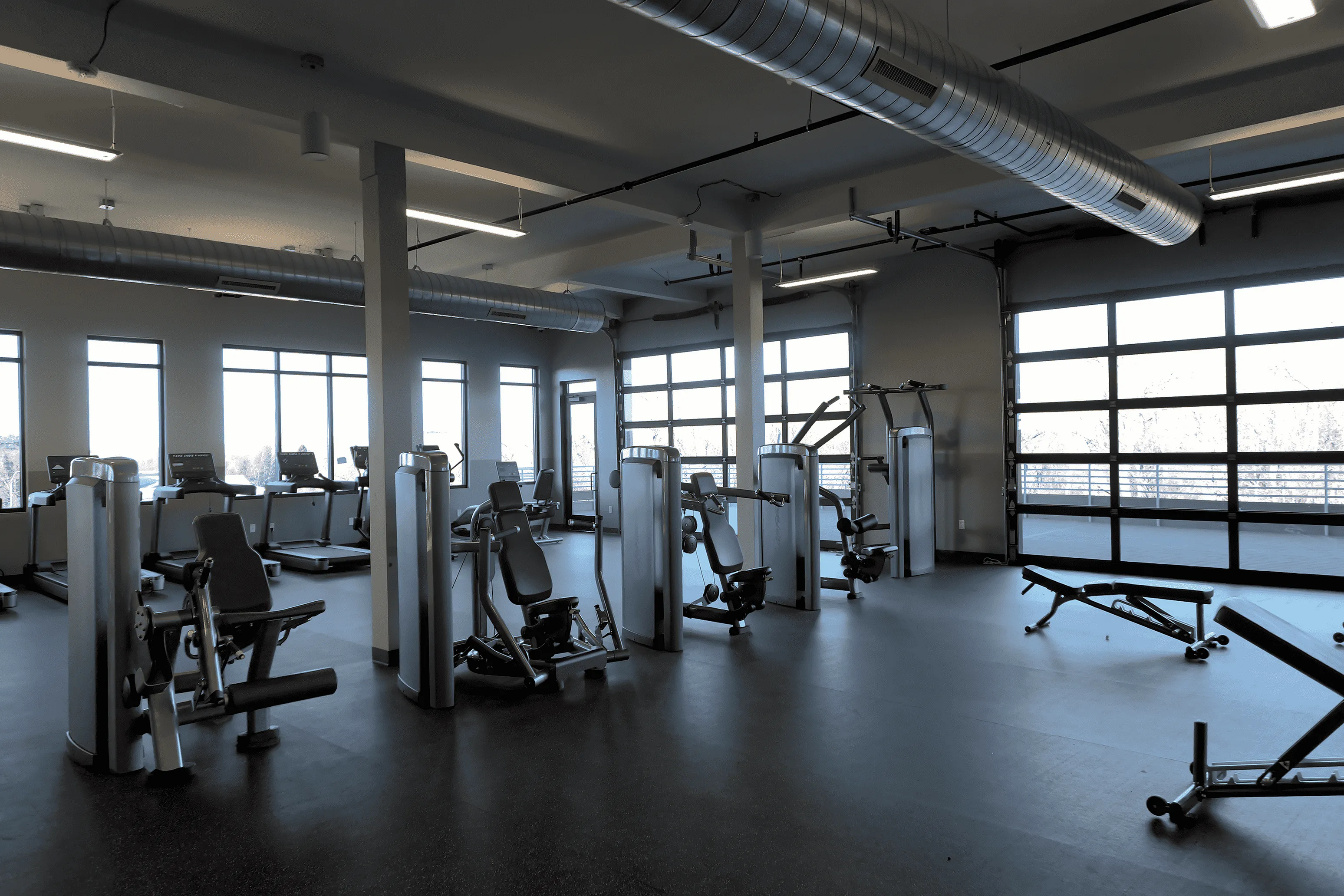 Modern fitness center with state-of-the-art exercise machines and large windows offering abundant natural light.