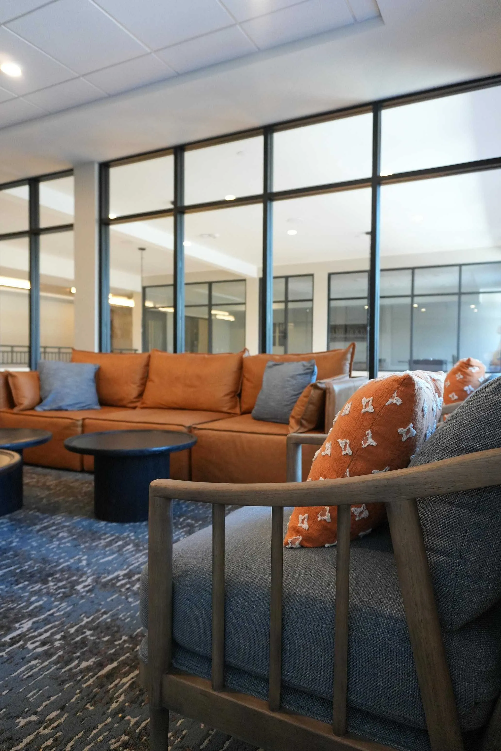 Elegant and cozy lounge area featuring modern orange couches with vibrant patterned pillows, complemented by chic dark coffee tables, perfect for relaxation and social gatherings.
