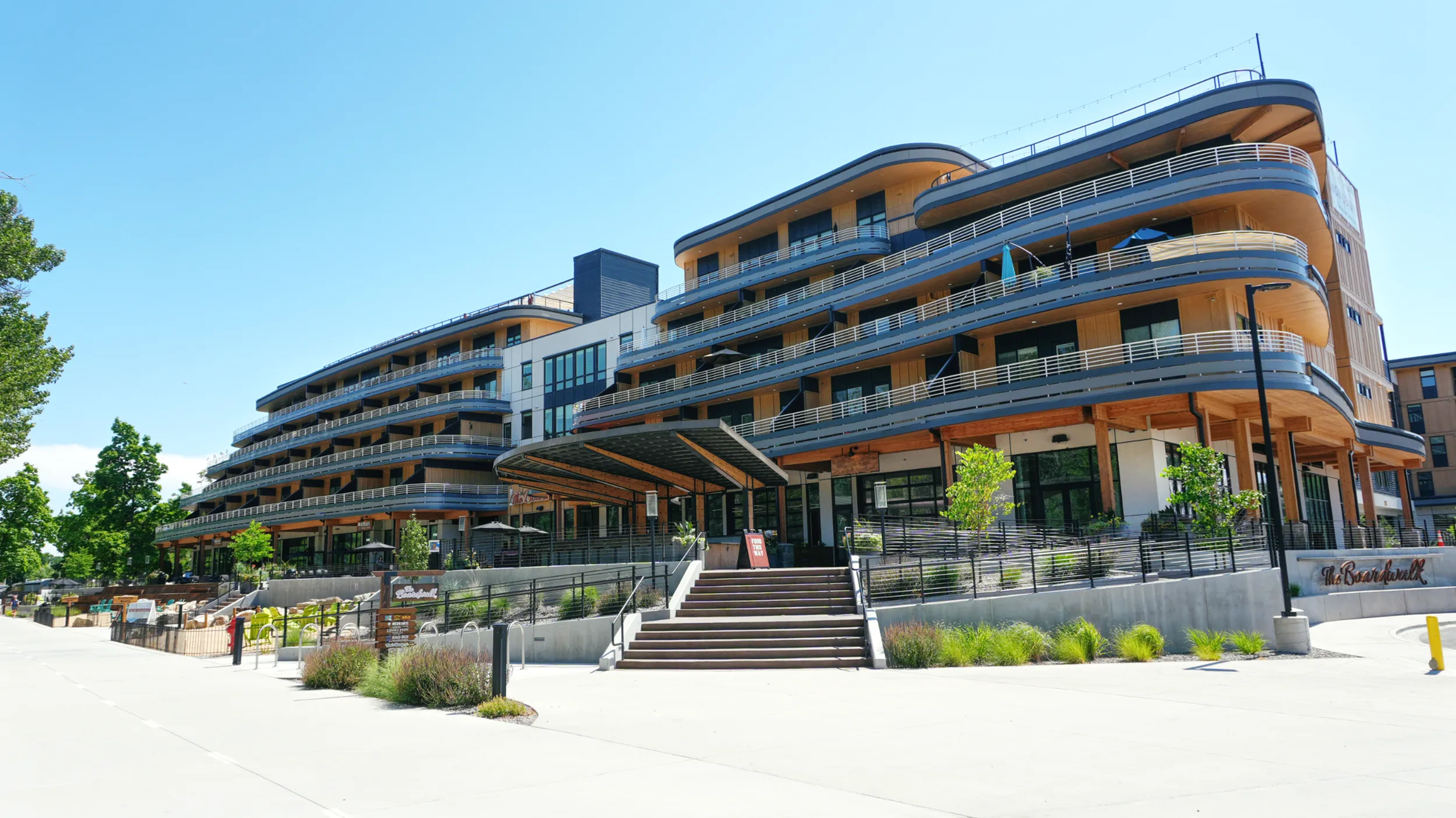 Contemporary curved apartment building with spacious balconies and lush greenery, offering a modern urban living experience.