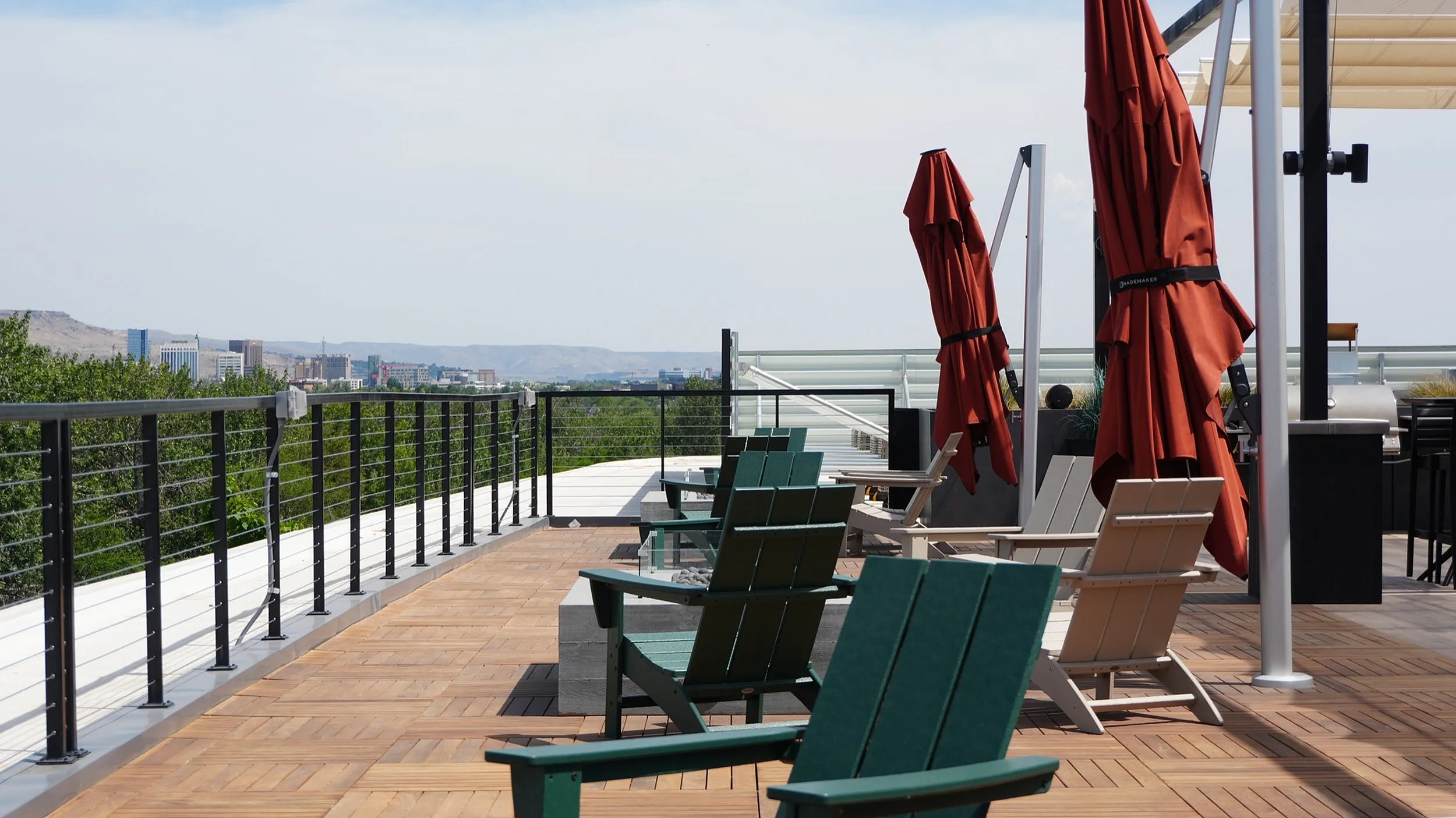 Spacious rooftop terrace with scenic city and mountain views, featuring comfortable seating and vibrant red umbrellas.