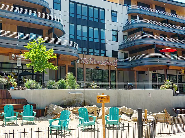 Charming modern apartment complex with a stylish facade, featuring balconies and a vibrant outdoor seating area perfect for relaxation.