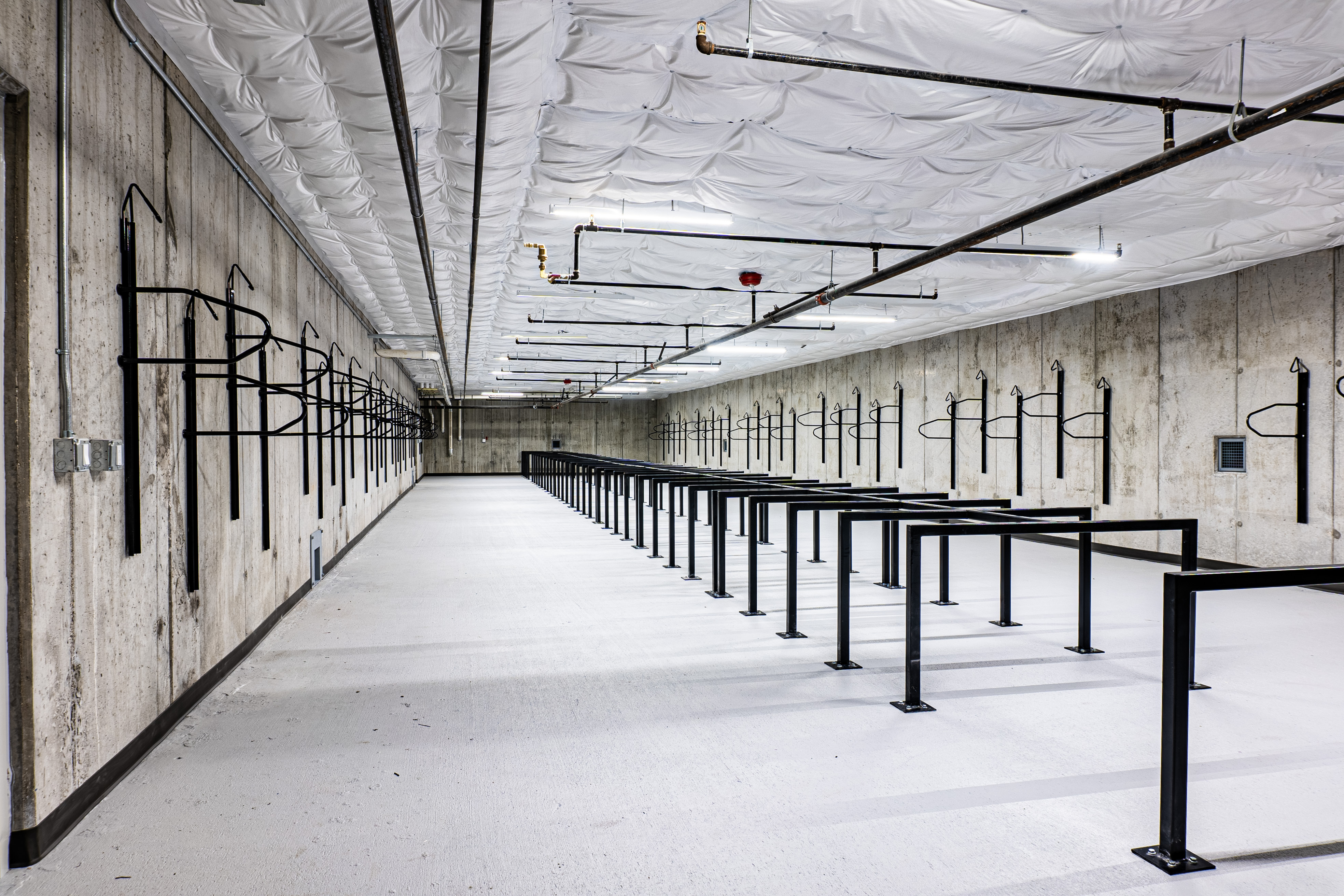 Modern bicycle storage area with ample hanging racks and sturdy concrete walls.