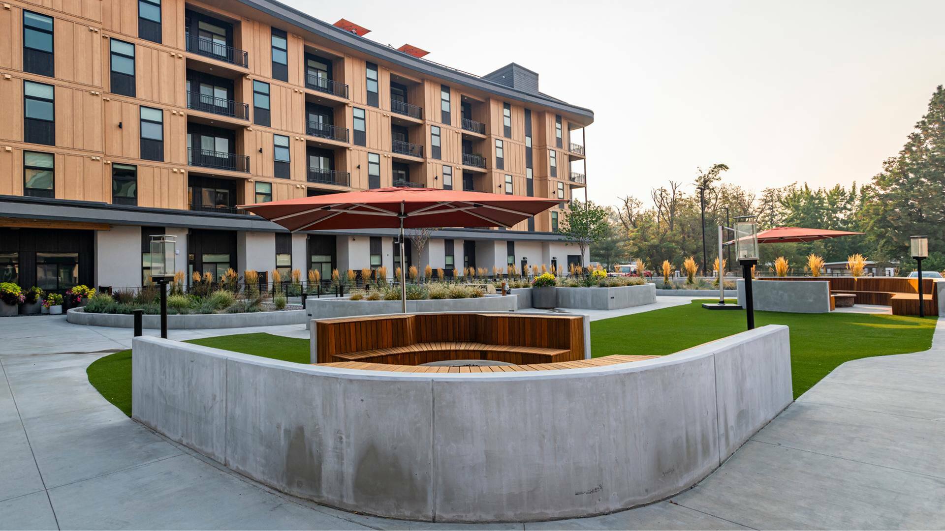 Modern courtyard with stylish seating, green lawns, and contemporary apartment backdrop.