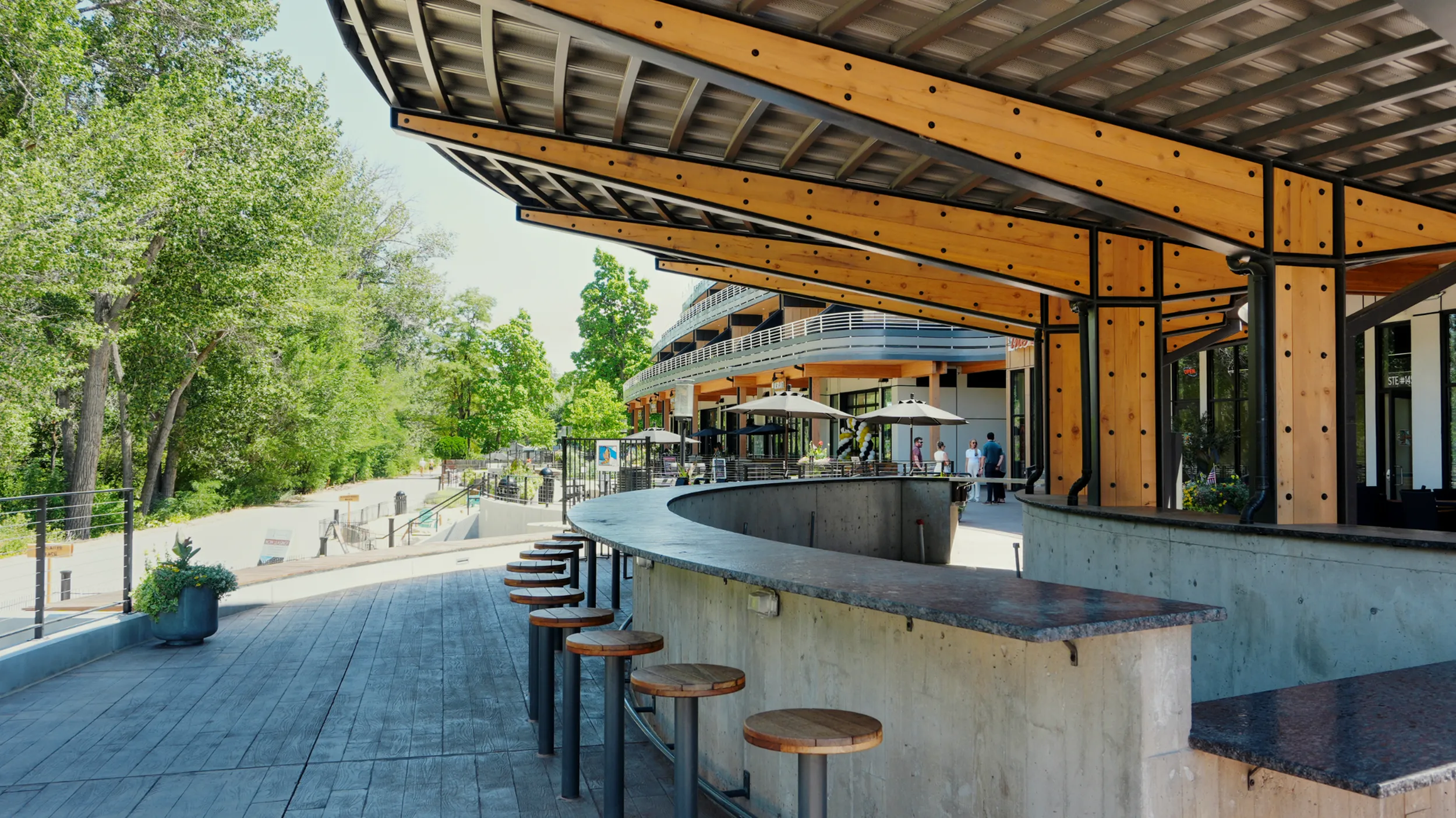 Chic outdoor seating area with modern architecture, featuring sleek wood and steel design, surrounded by lush greenery.