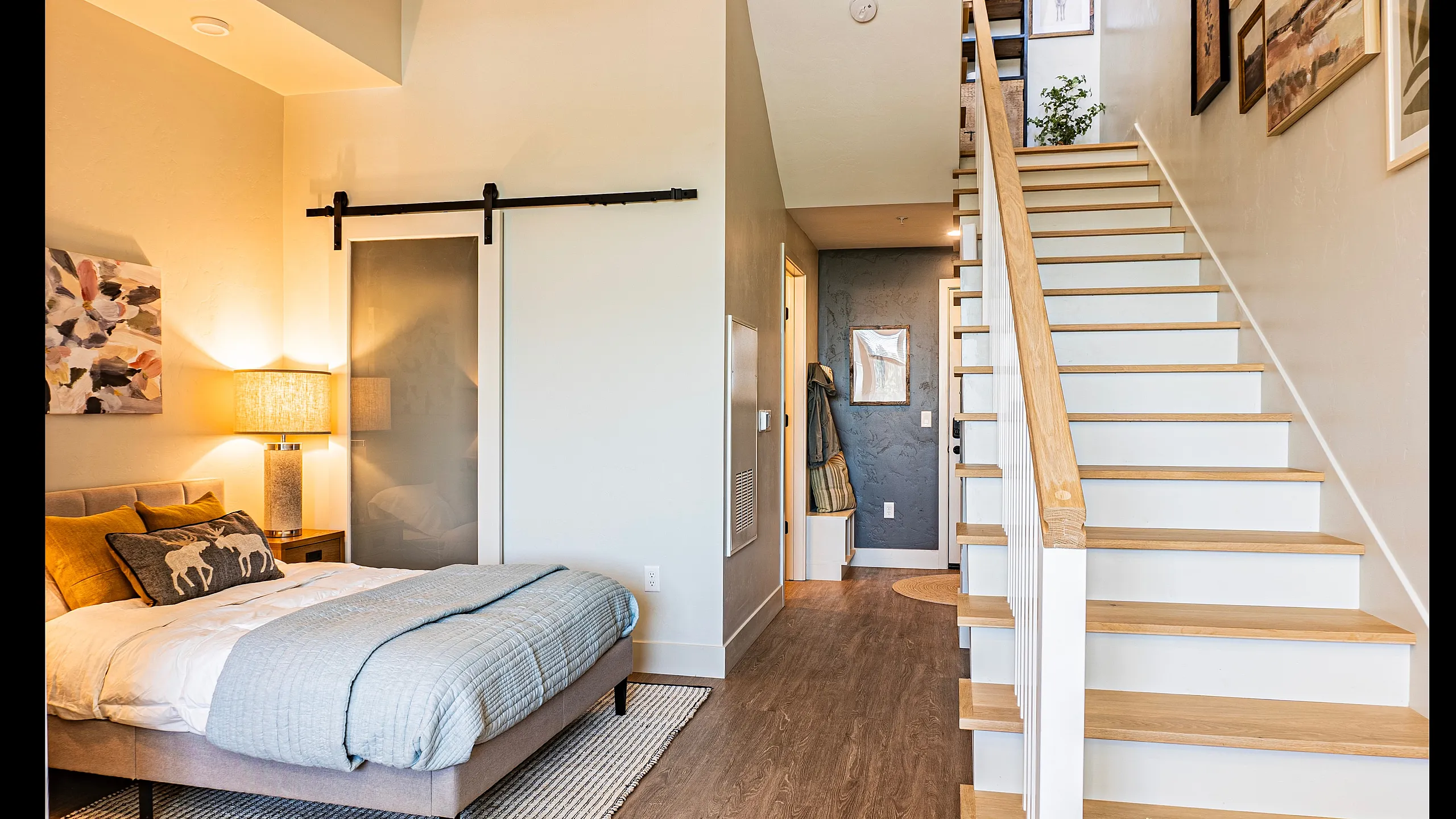 Inviting modern bedroom with stylish decor, soft lighting, and a wooden staircase leading to an upper level.