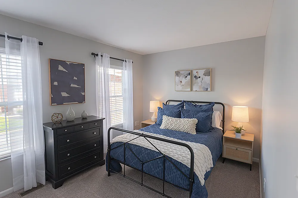 Cozy and inviting bedroom with modern decor, featuring a plush bed, elegant lamps, and natural light from large windows.