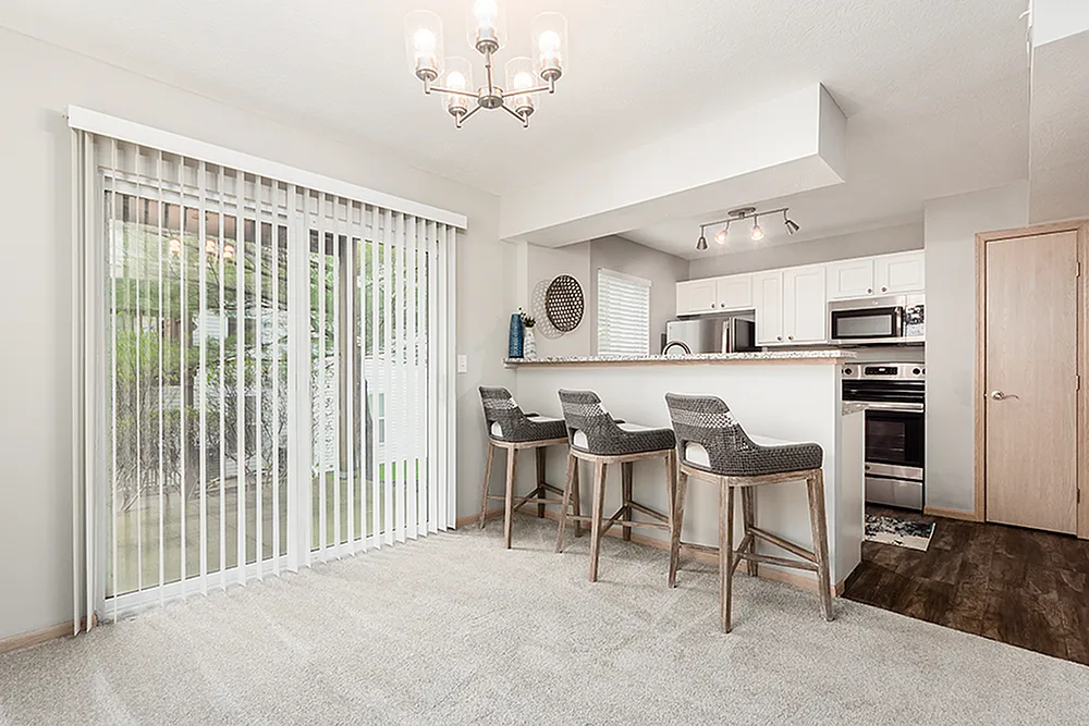 Chic kitchen with modern appliances, stylish bar seating, and ample natural light from sliding glass doors.